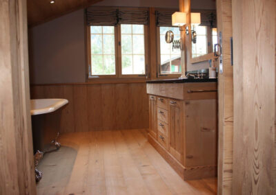 Badezimmer mit maßgefertigtem Waschtisch aus Massivholz und Naturstein – Schreinerarbeit für exklusiven Innenausbau.