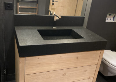 Moderner Badezimmer-Unterschrank aus massivem Holz mit schwarzer Steinplatte – eleganter Innenausbau in Massivholz.