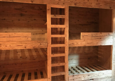 Innenausbau aus massivem Holz mit integrierten Stockbetten und Leiter – maßgefertigte Schreinerarbeit.