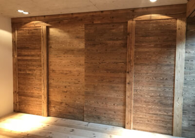 Verkleidung aus Massivholz im Innenausbau – rustikale Schiebetüren in hochwertiger Schreinerarbeit.