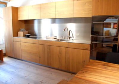 Holzküche mit Edelstahl-Rückwand und modernen Einbaugeräten von Aegerter Küchen AG