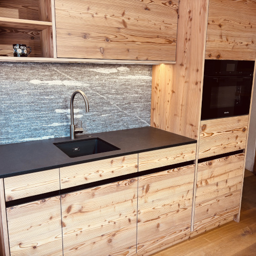 Lärchenküche Chiavenna mit gebürsteten Holzfronten und dunkler Arbeitsplatte