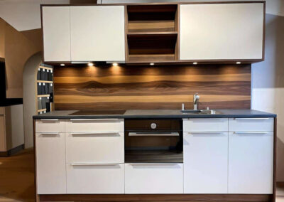 Moderne Küche mit Holzrückwand, weissen Fronten und integrierten Einbaugeräten